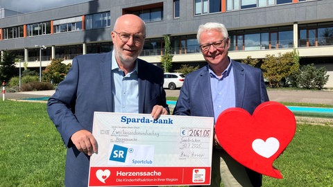 SR Sportclub-Vorsitzender Roman Bonnaire übergibt den Spendenscheck an Herzenssache-Beauftragten Thomas Rosch