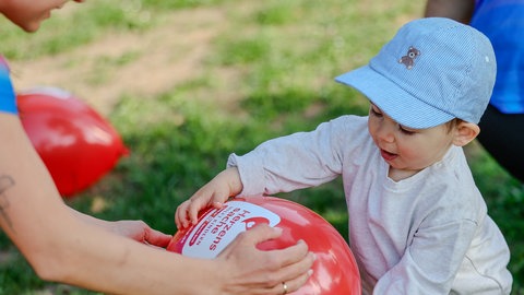 Kleinkind spielt mit Herzenssache-Luftballon beim Gutenberg Halbmarathon 2026