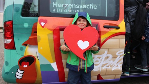 Junge hält Herz hoch