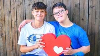Lukas (links) und Mattheo (recht, Junge mit Down Snydrom) halten das Herzenssache-Herz