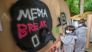 Zwei Jungs besprühen eine Leinwand