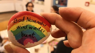 Ein bunter Stein, auf dem die Worte "Bad Neuenahr wird wieder bunt" stehen, wird hochgehalten